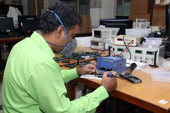 Amit soldering and testing a PCB for the microcontroller lab